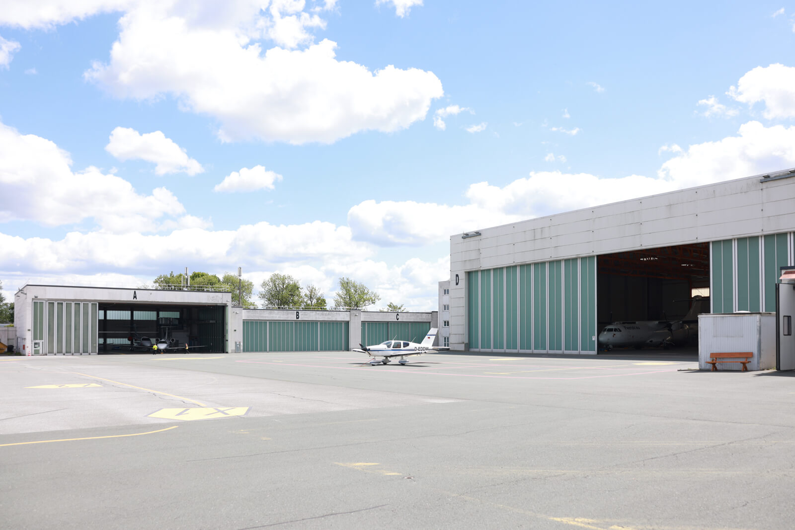 Das Bild zeigt den Hangar des Flughafen Hof-Plauen mit einem kleinen Sportflugzeug davor